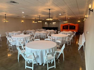 Birthday party ballroom with white round tables and a bounce house
