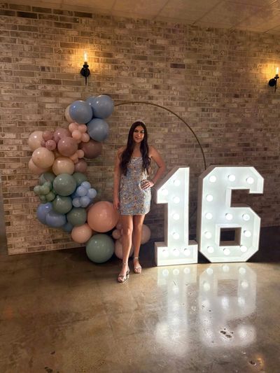 Sweet 16 party with marquee numbers and a pastel balloon arch