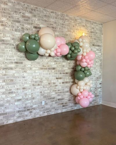 Sage, pink, and cream balloon garland on the white brick wall