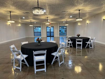 Ballroom with black linen round tables and elegant chandeliers