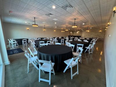 Ballroom with black round tables and white folding chairs
