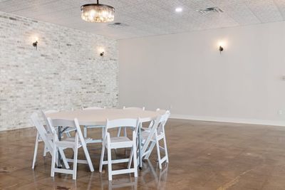 White brick accent wall with a round table and chandelier