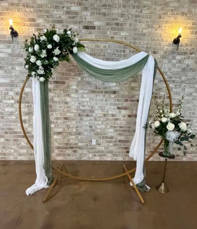 Gold circle wedding arch with greenery and sage draping