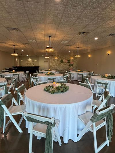 Reception round table with greenery centerpiece and sage chair sashes